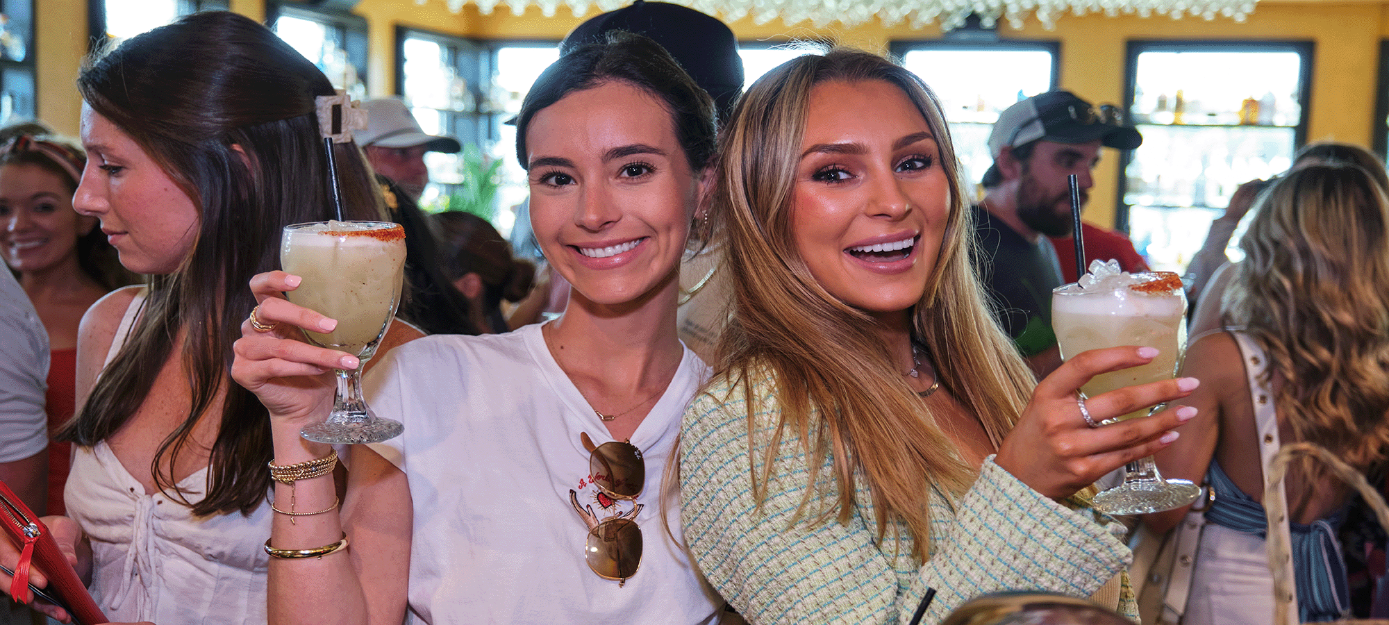 Two women smile at the camera while holding margaritas in the Cactus Club.