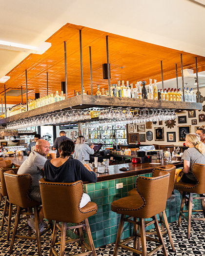 A group of people sit at the bar enjoying cocktails.