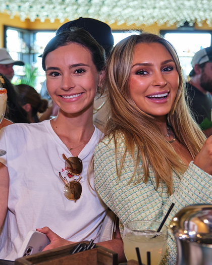 Two women smile at the camera while holding margaritas in the Cactus Club.