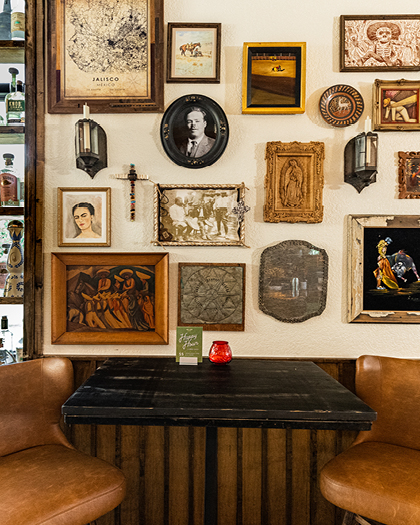 A wall of decorative frames hang above a bar table.